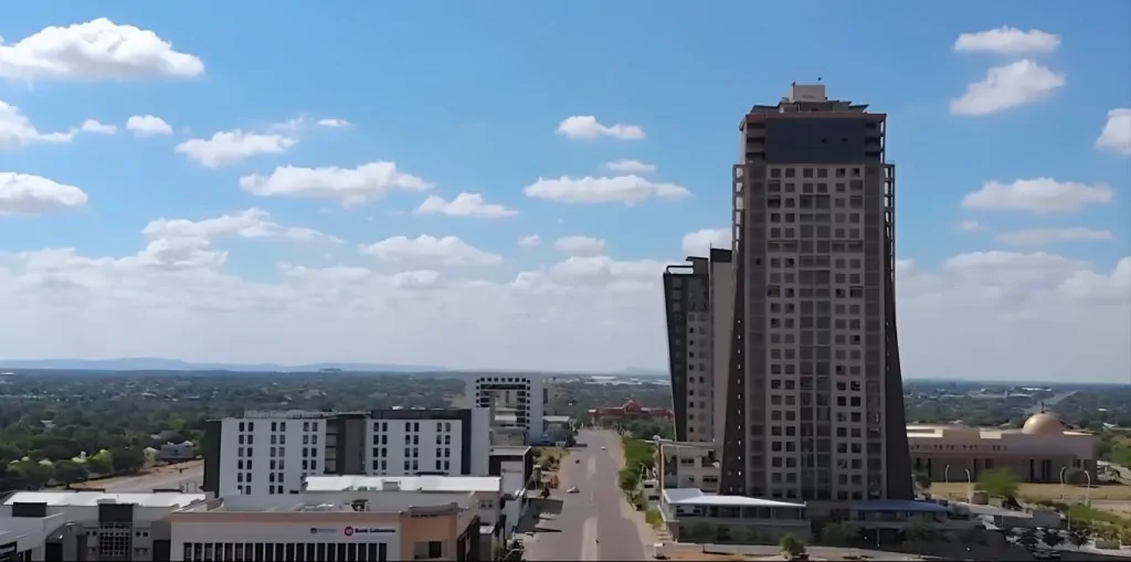 Gaborone aerial photo. It shows a few buildings and a bright bluw sky with a couple of clouds.