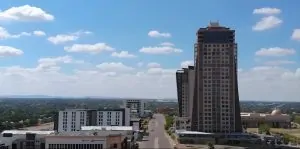 Gaborone aerial photo. It shows a few buildings and a bright bluw sky with a couple of clouds.
